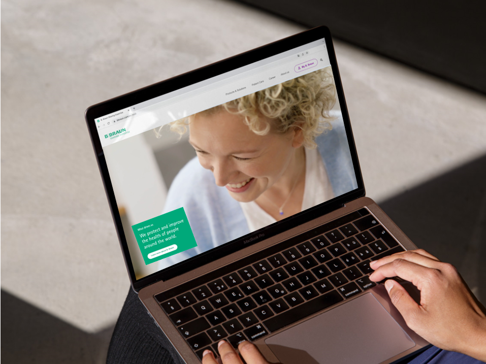 A laptop with the B. Braun website open and a hand resting on the bottom right of the laptop. 