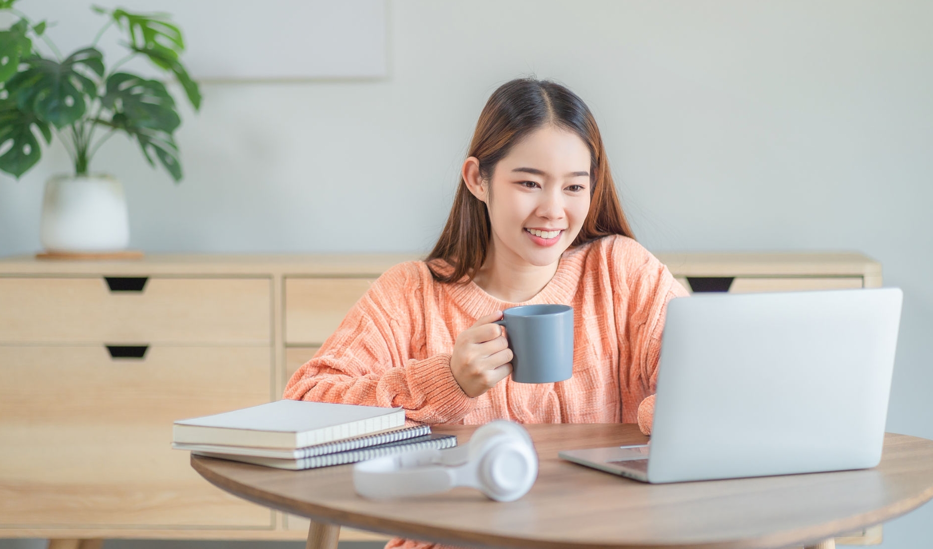 Young woman working on her notebook computer at her home. Work from home concept.
