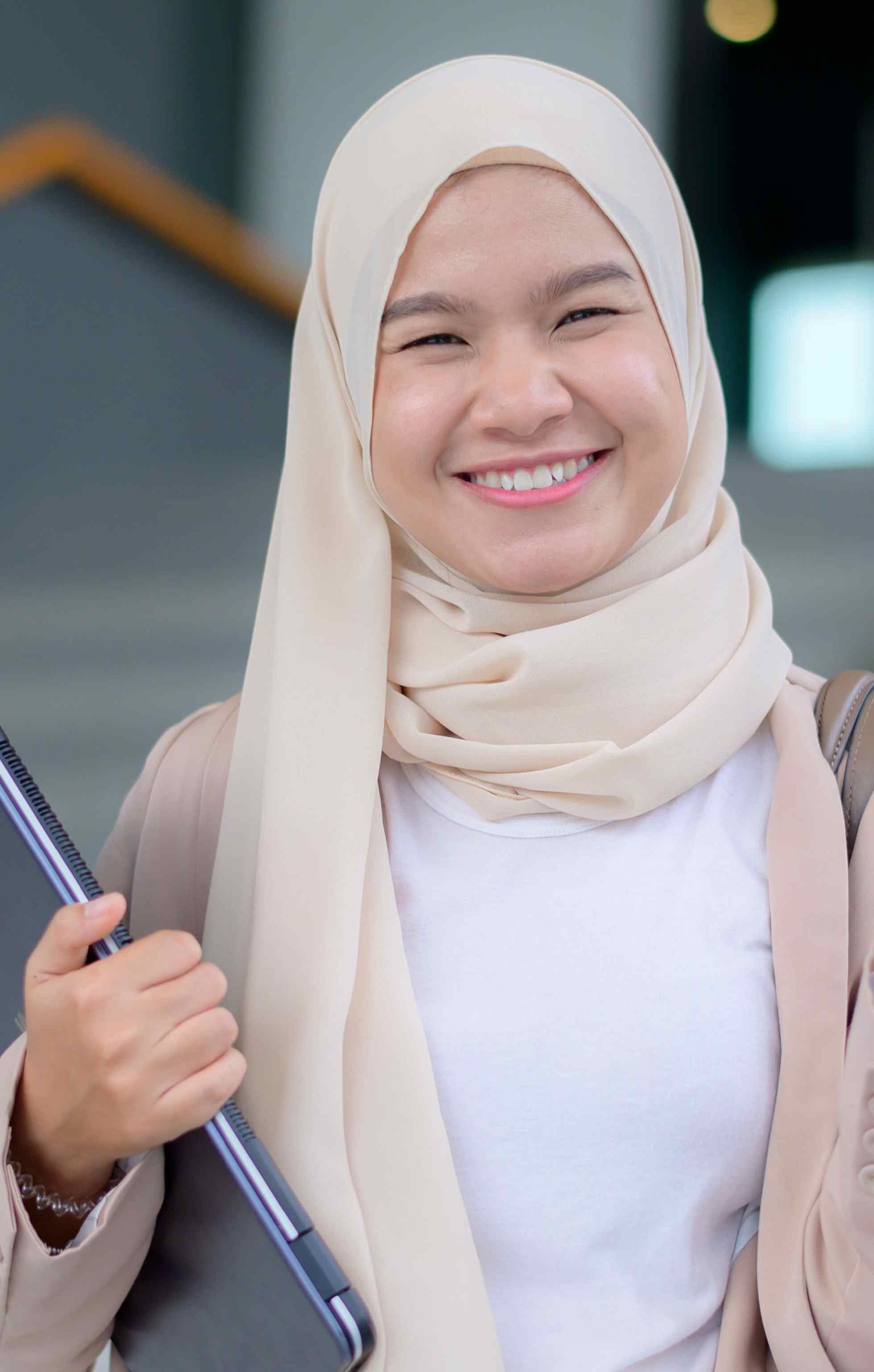 An individual smiling while holding a laptop