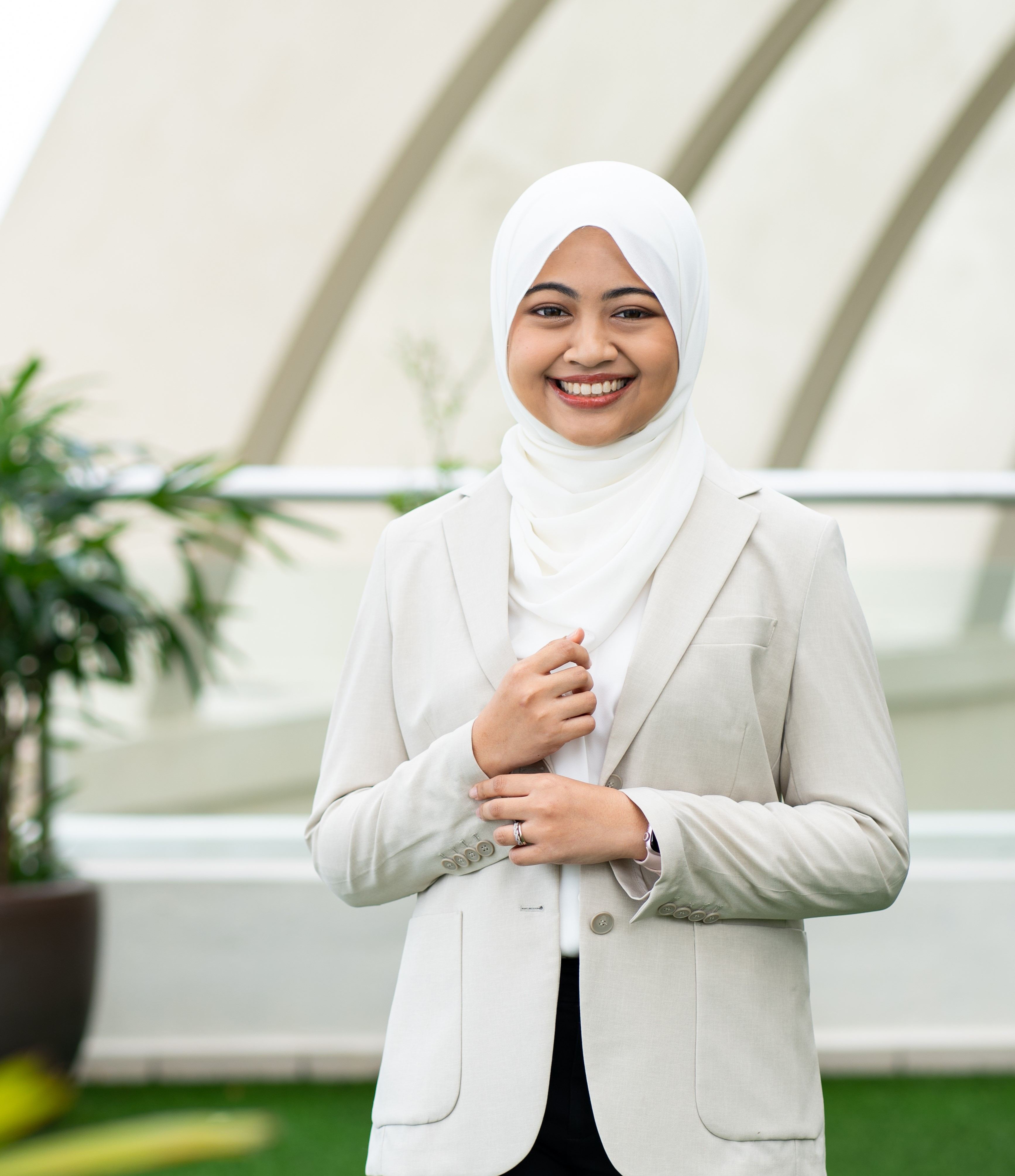 An individual smiling with a confidence and intelligence, holding a laptop.
